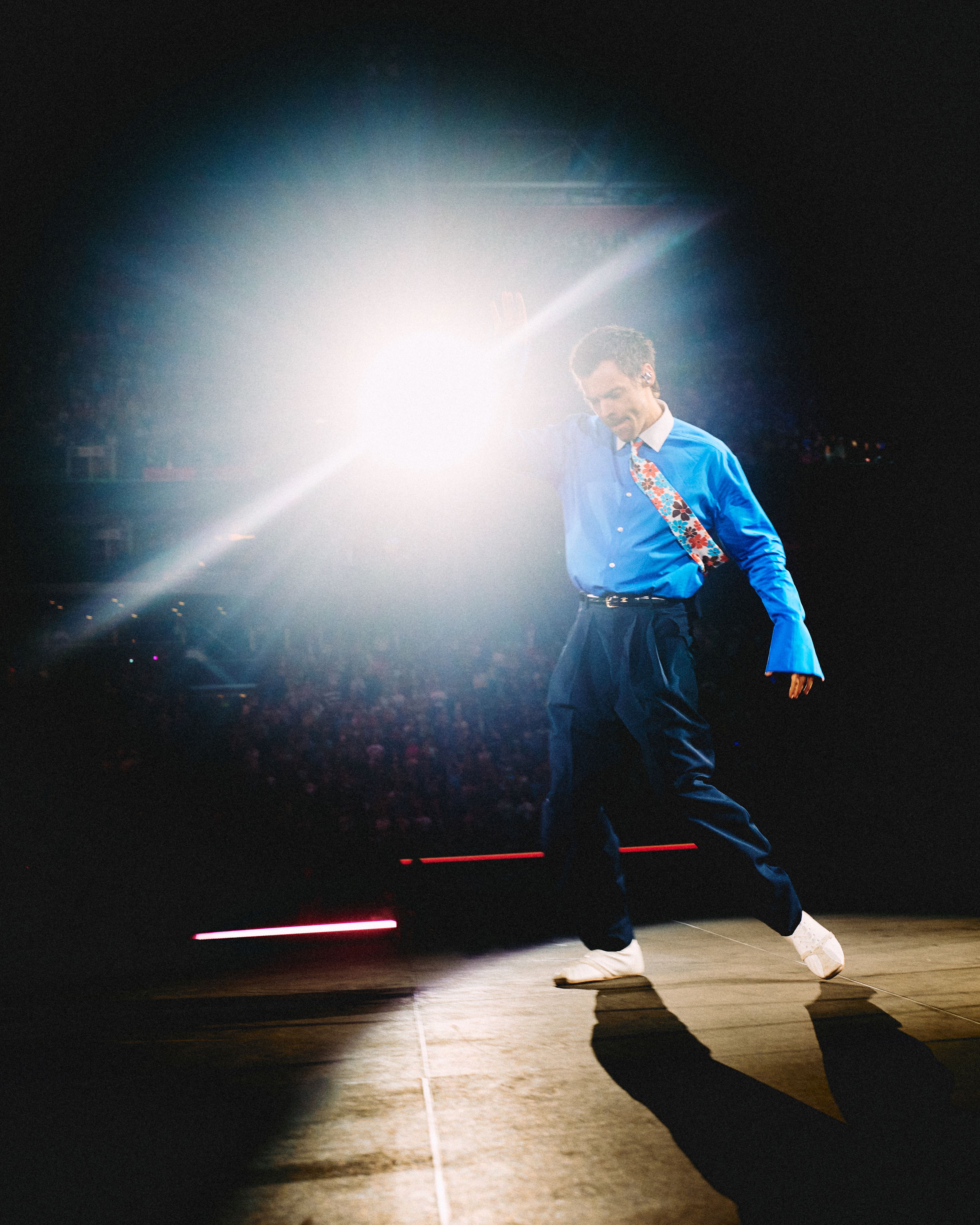 Harry Styles on stage with stage light behind him